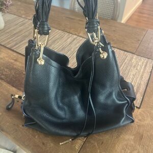 A beautiful Stuart Weitzman black leather purse with gold accents.